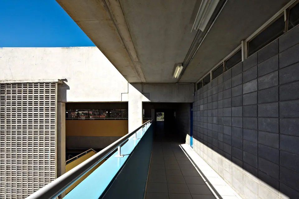 Um longo corredor com uma grade azul entre dois edifícios
