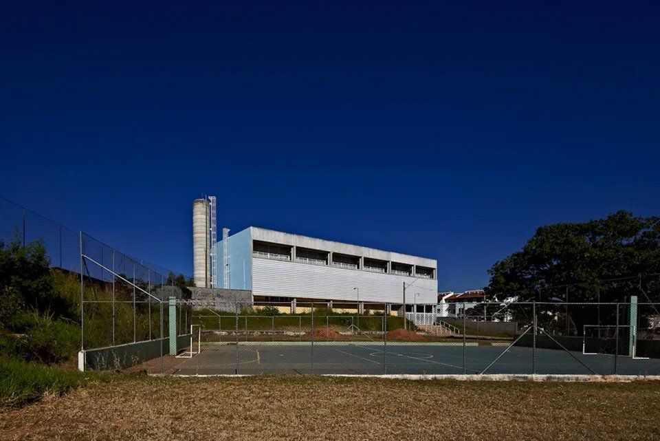 Um grande prédio branco com uma quadra de basquete na frente.
