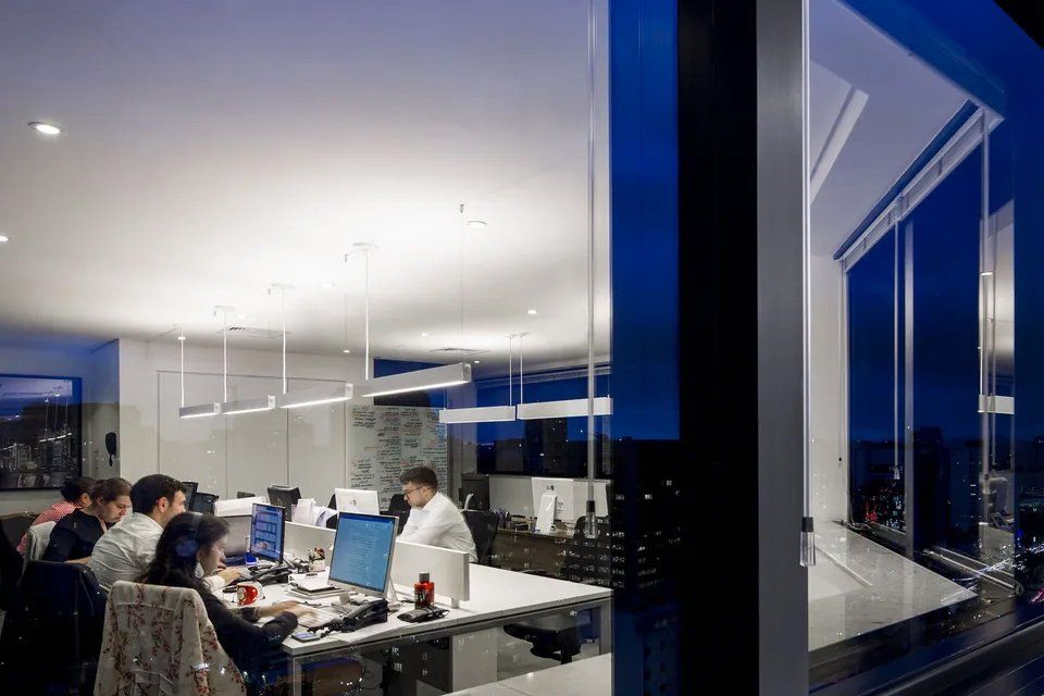 Um grupo de pessoas está sentado em mesas de um escritório.