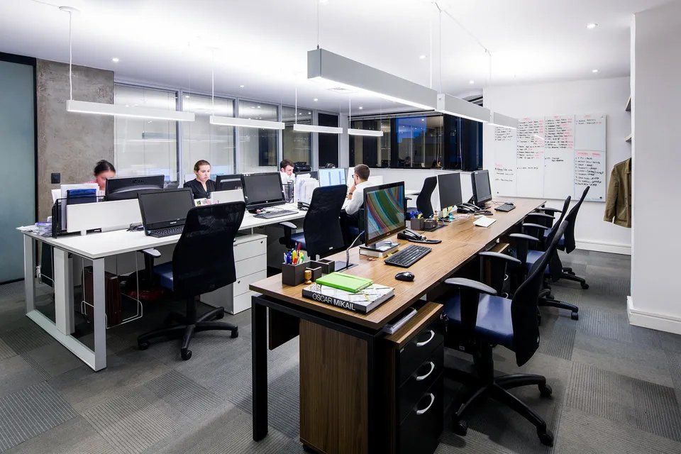 Um grupo de pessoas está sentado em mesas de um escritório.