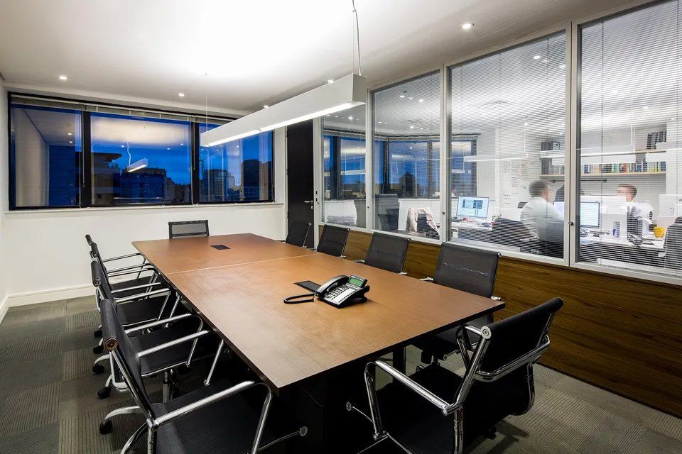 Uma sala de conferências com uma longa mesa e cadeiras e um telefone.