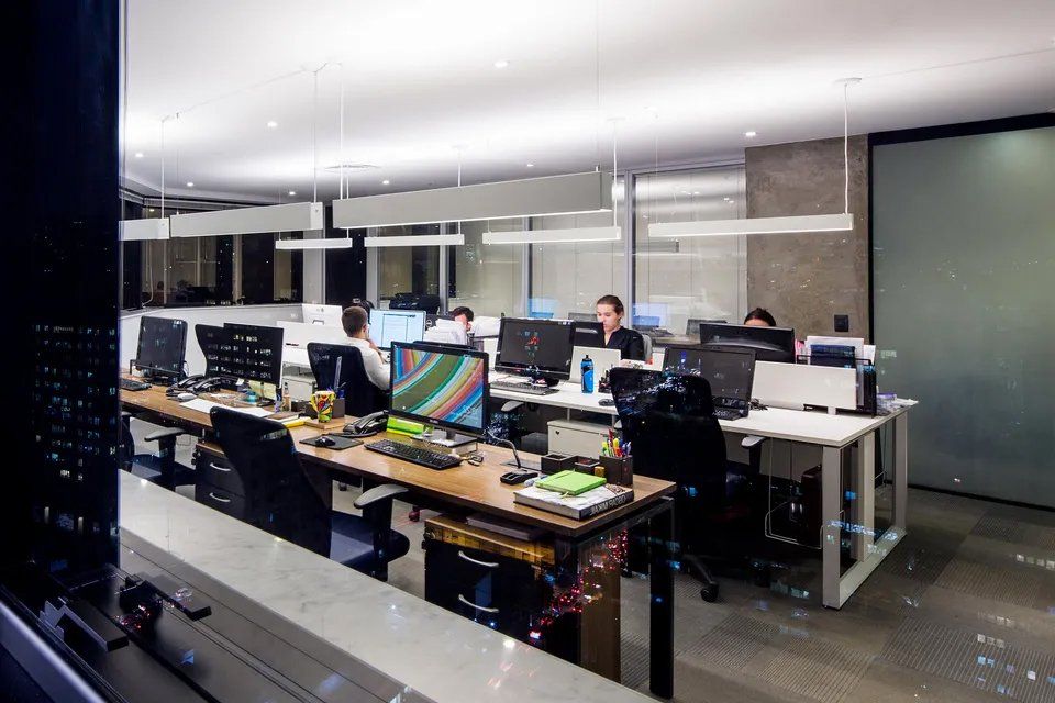 Um grupo de pessoas está sentado em mesas de um escritório.