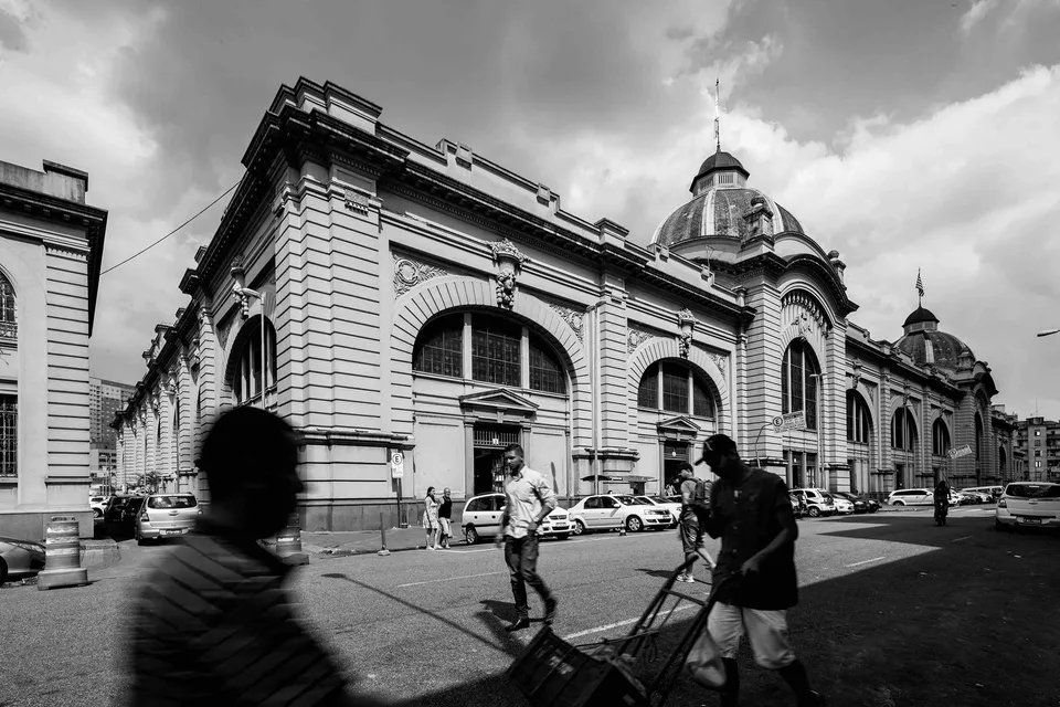 Uma foto em preto e branco de pessoas andando em frente a um grande edifício