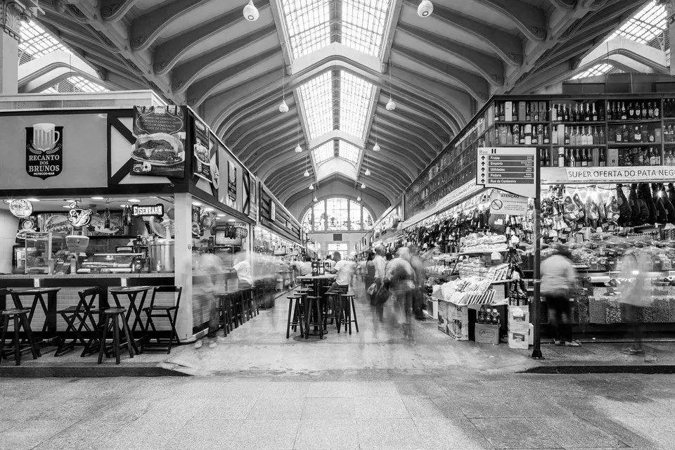Uma foto em preto e branco de um mercado com pessoas andando.