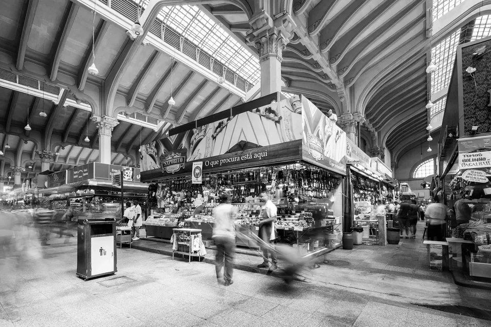 Uma foto em preto e branco de um mercado com pessoas andando.