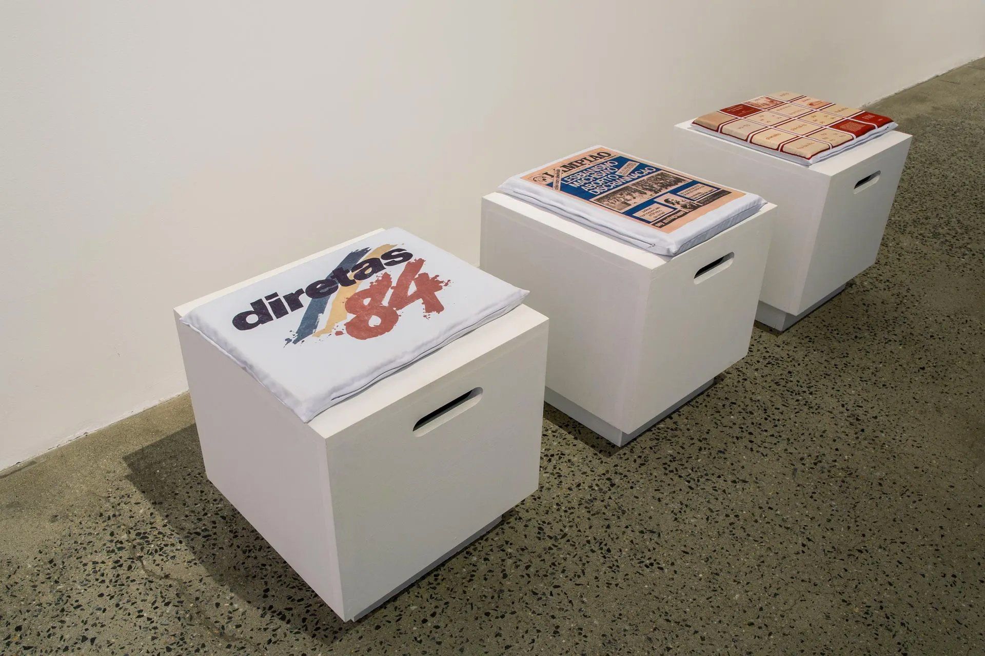 Três pufes estão sentados um ao lado do outro em um chão de concreto.