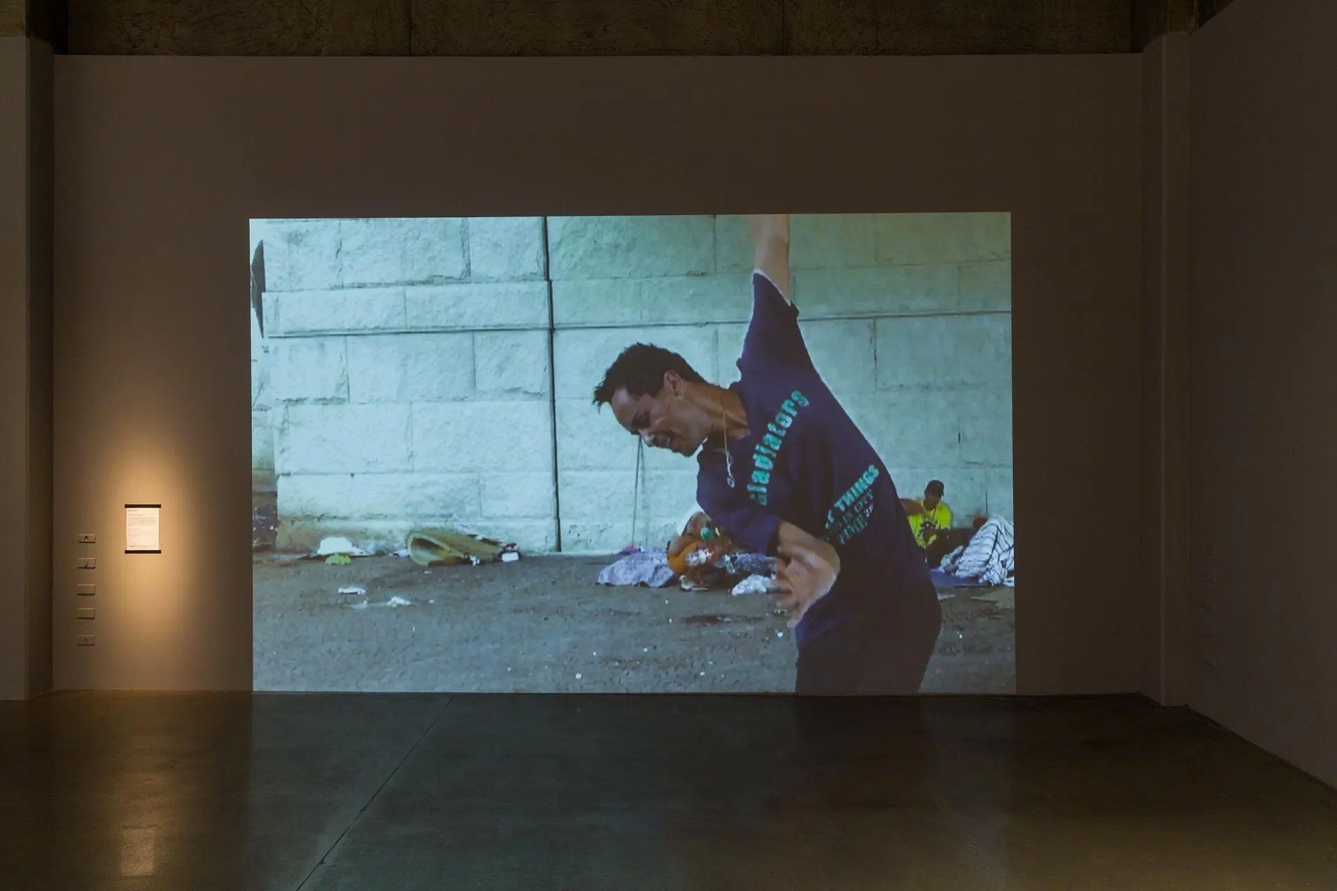 Um homem de camisa azul está parado em frente a uma parede.
