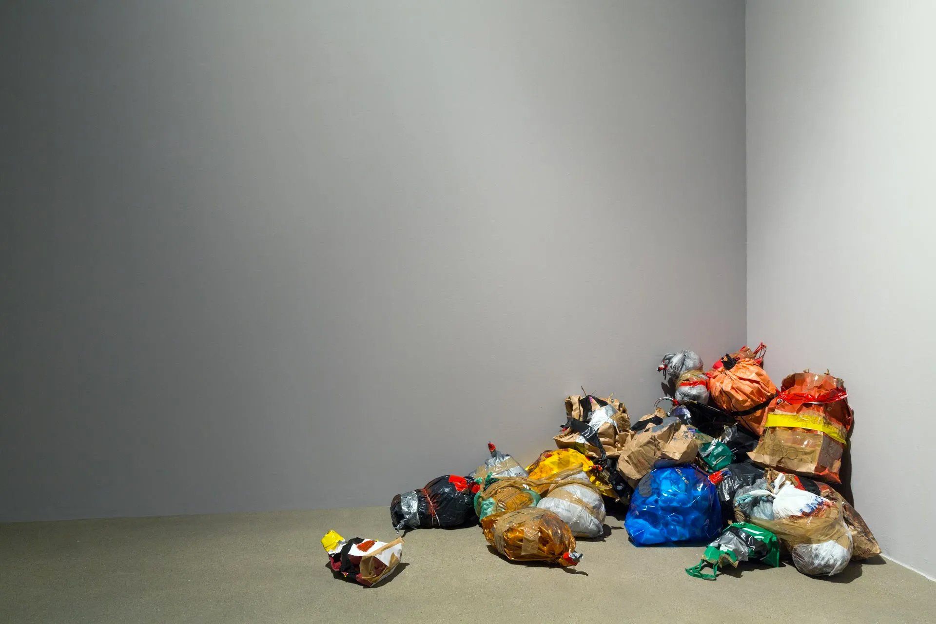 Um monte de sacos de lixo estão no chão, no canto de uma sala.