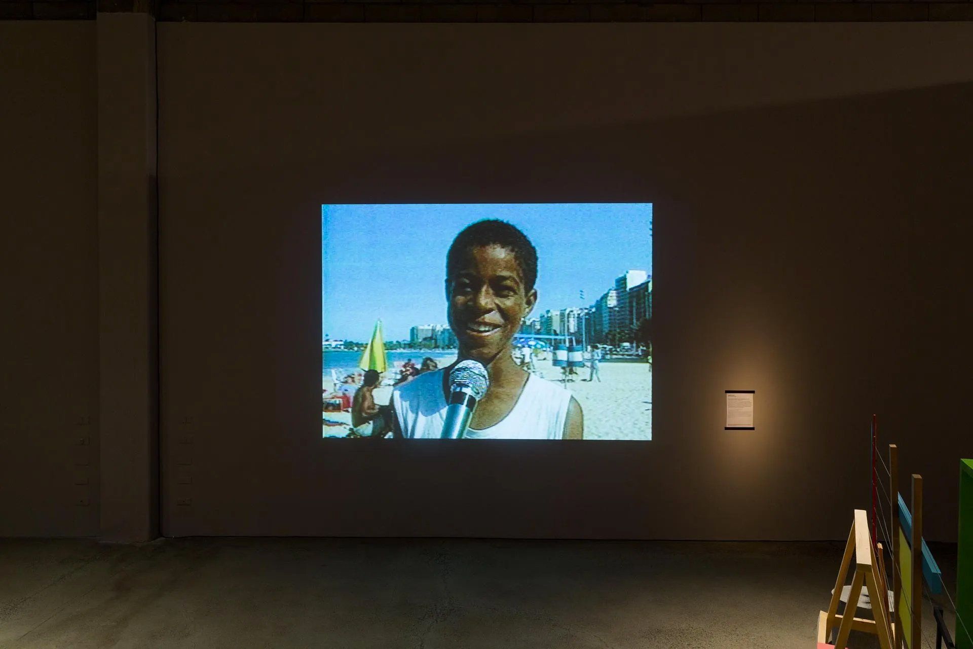 Uma tela de projetor projeta a imagem de um menino na praia.