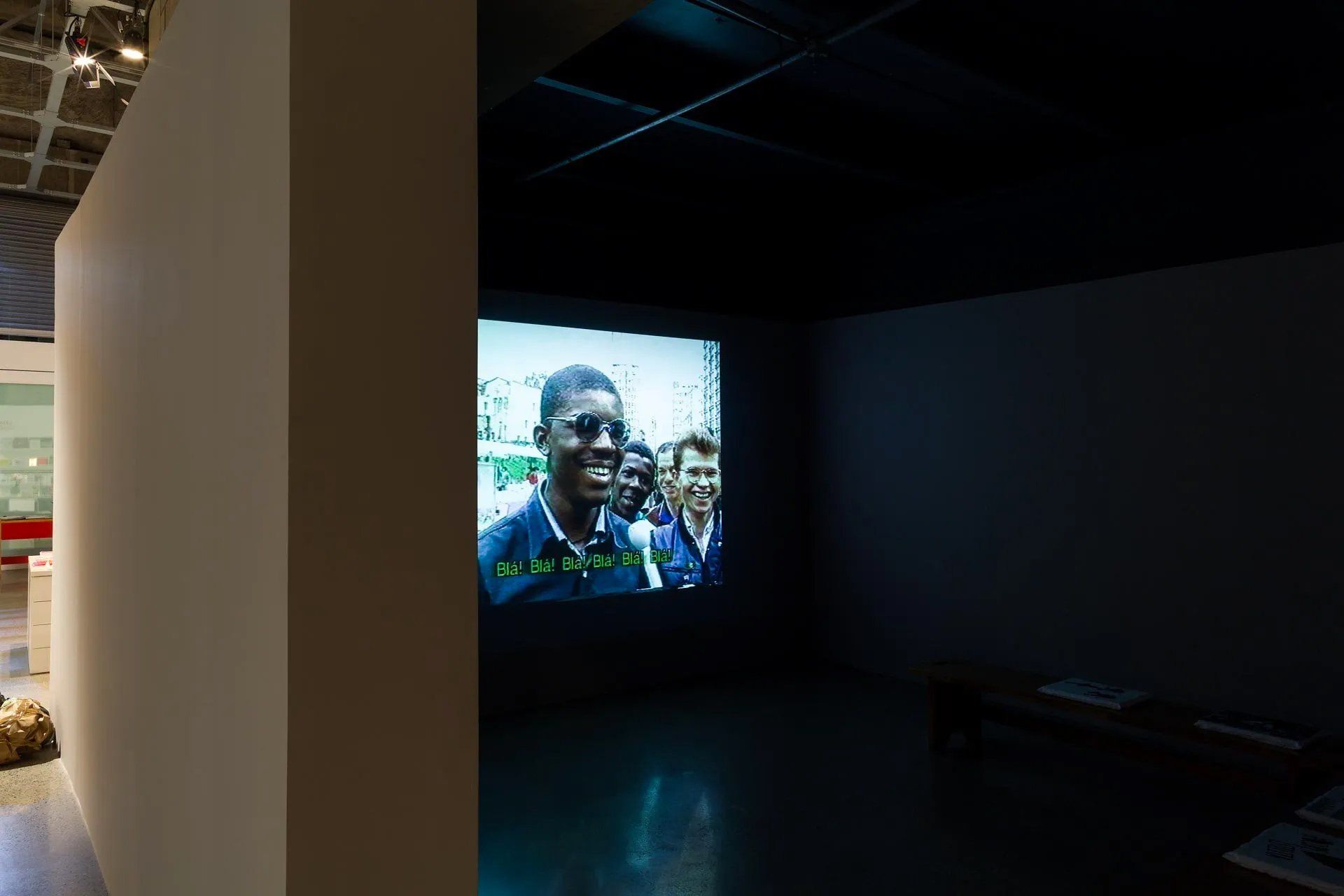 Um homem está sorrindo em uma tela em um quarto escuro.