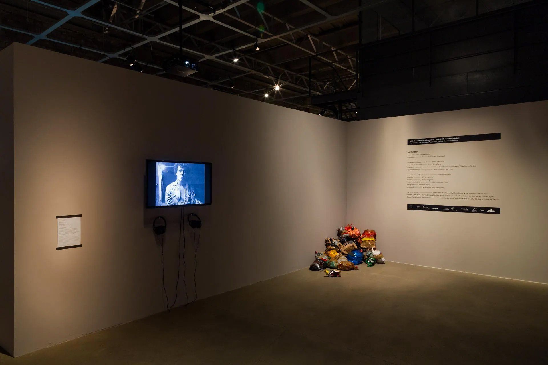 Uma sala com uma televisão na parede e uma pilha de brinquedos no chão.