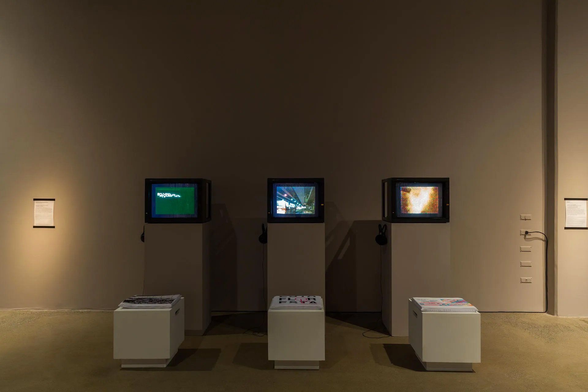 Três televisões estão expostas em uma sala escura.