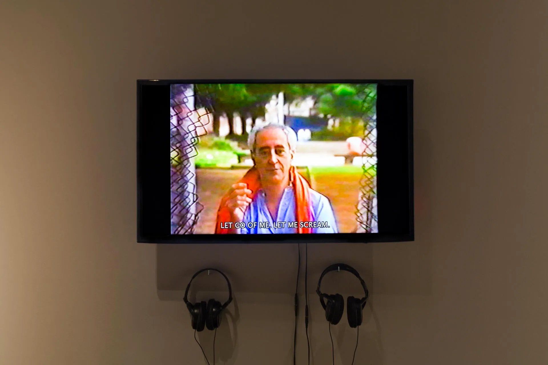 Uma televisão está pendurada na parede ao lado de um par de fones de ouvido.