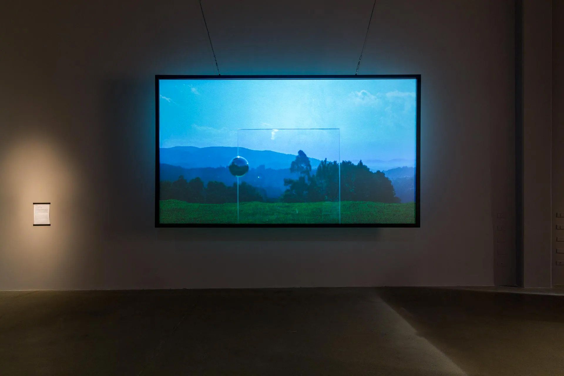 Uma grande tela está pendurada na parede de um quarto escuro.