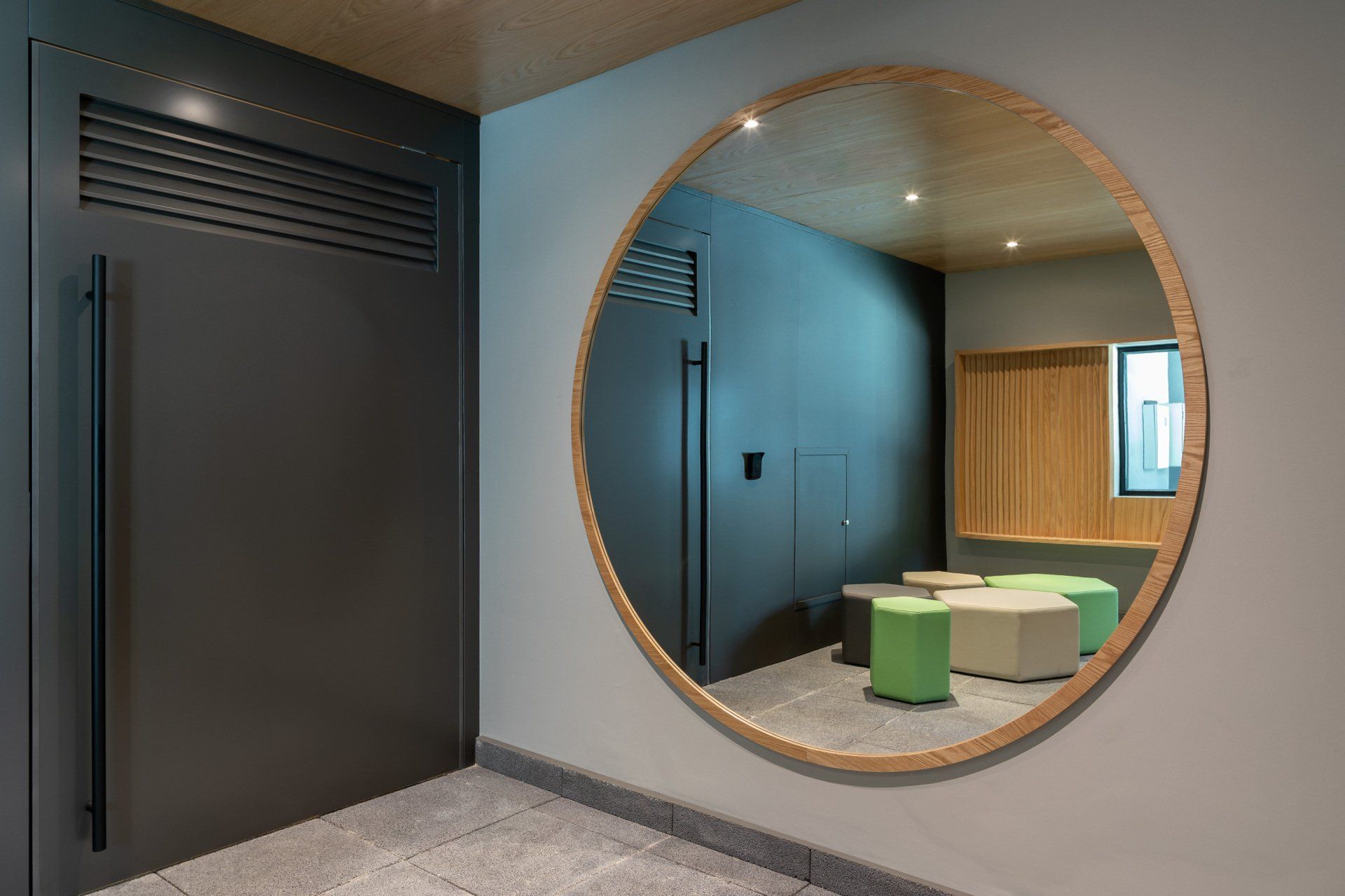 Um grande espelho redondo está pendurado na parede de um corredor.