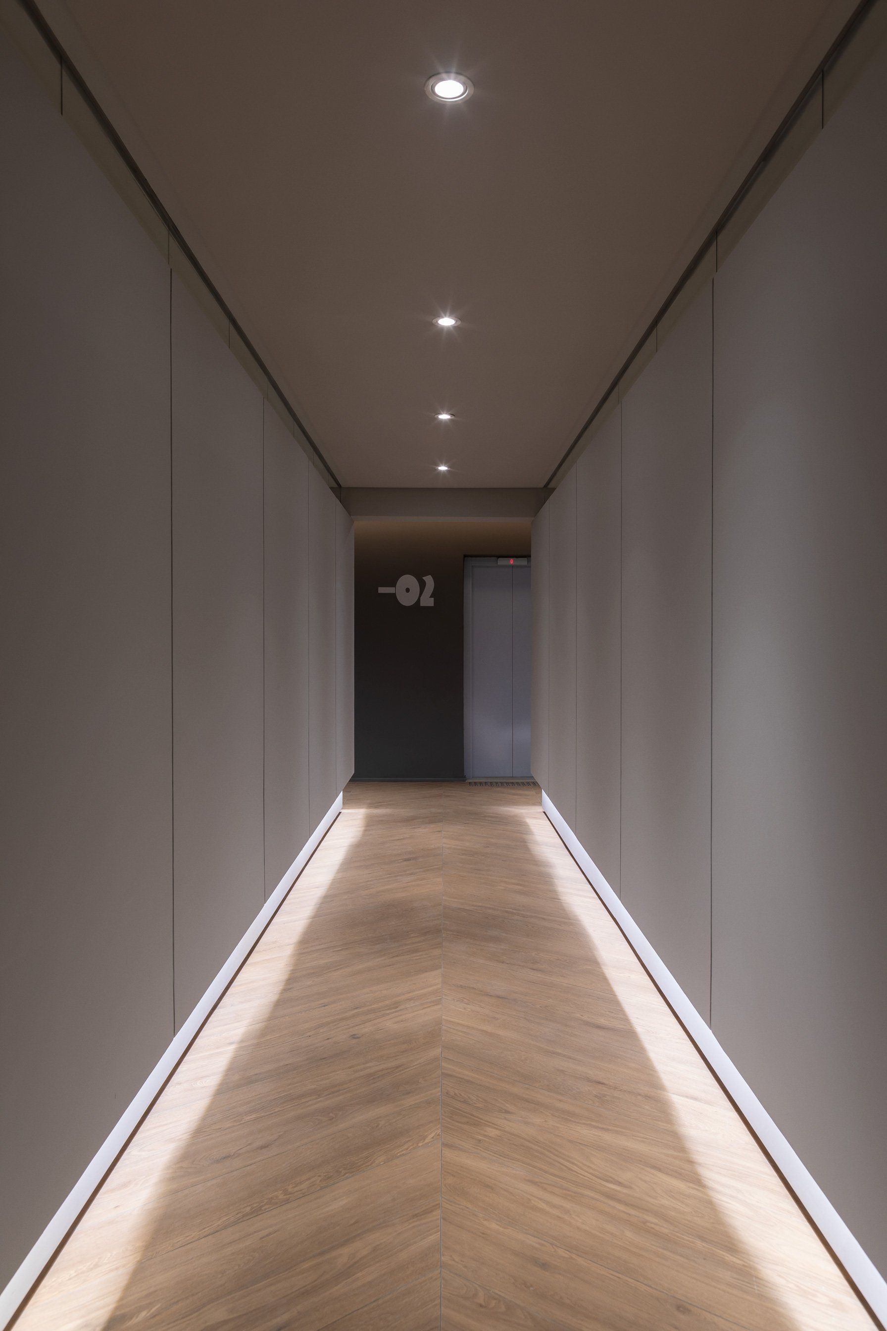 Um longo corredor com piso de madeira e paredes brancas