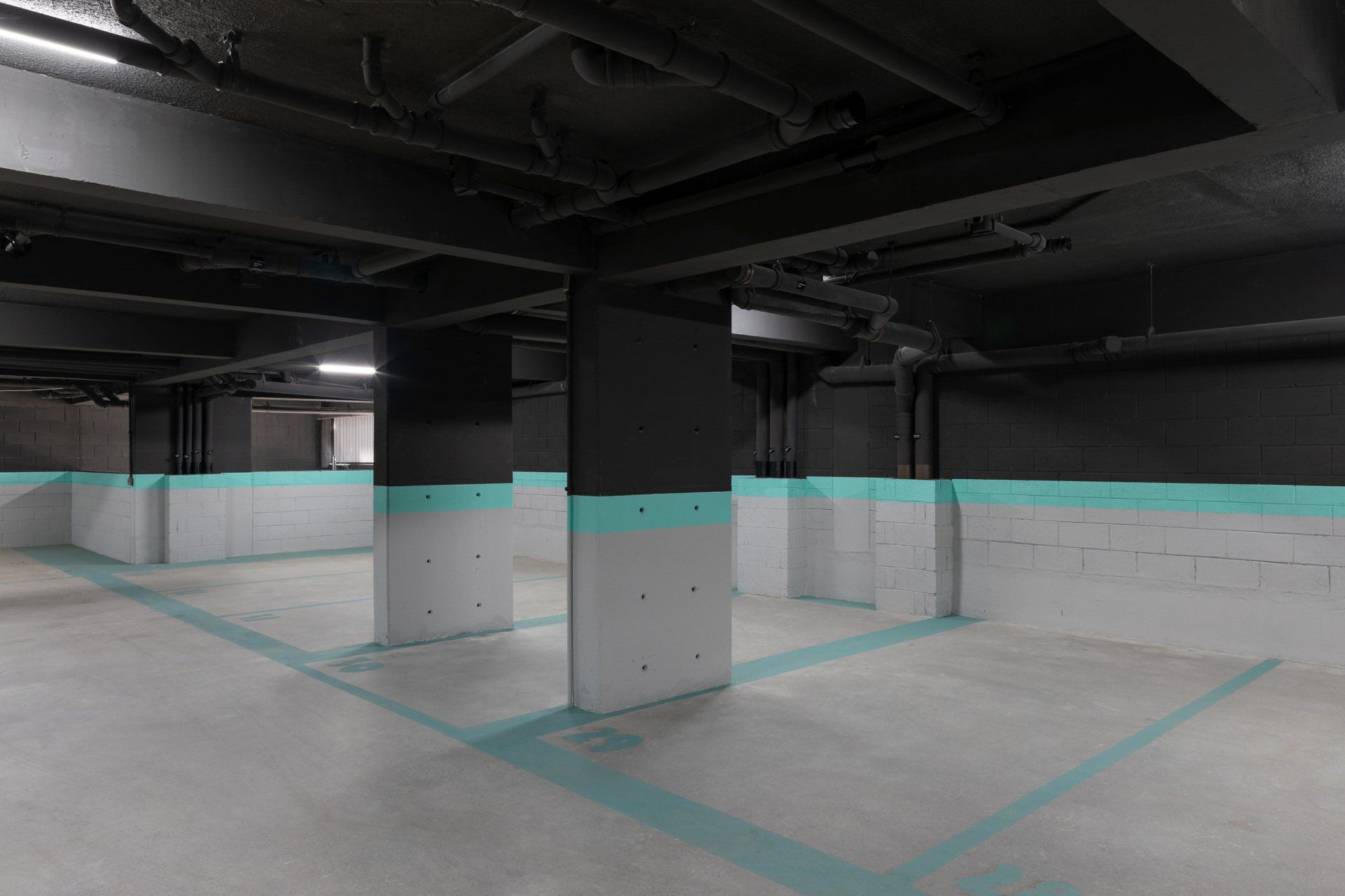 Uma garagem vazia com paredes pretas e linhas azuis no chão.