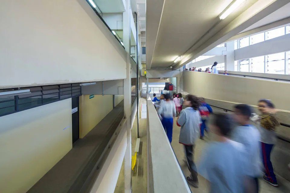 Um grupo de pessoas está andando pelo corredor de um prédio.