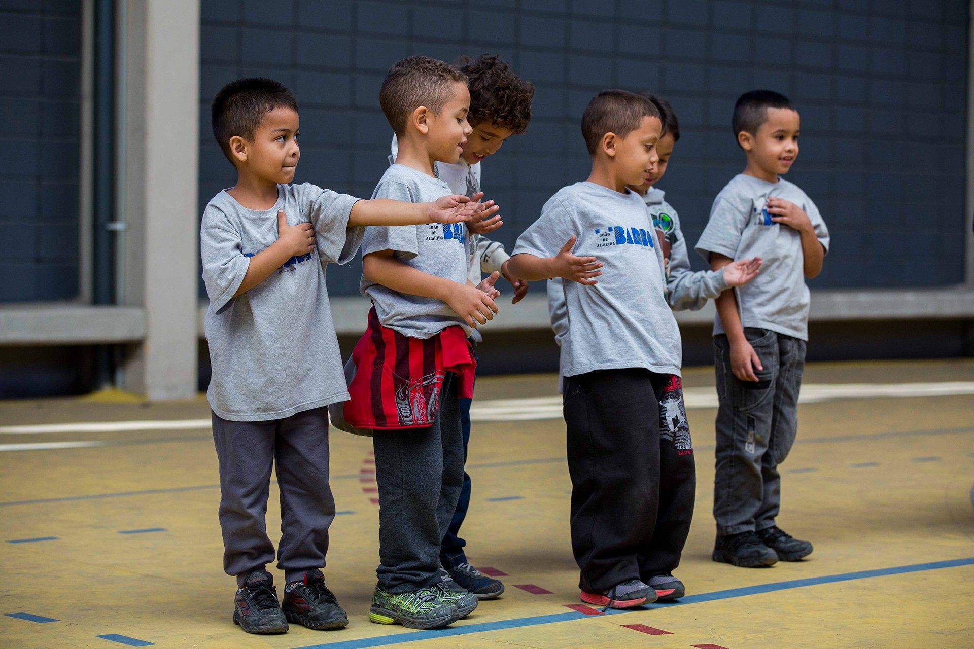 Um grupo de meninos está um ao lado do outro em uma quadra.