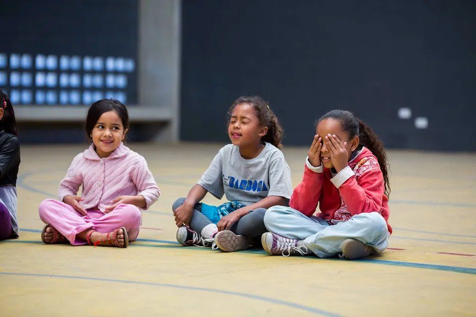 Um grupo de meninas está sentado no chão com as pernas cruzadas.