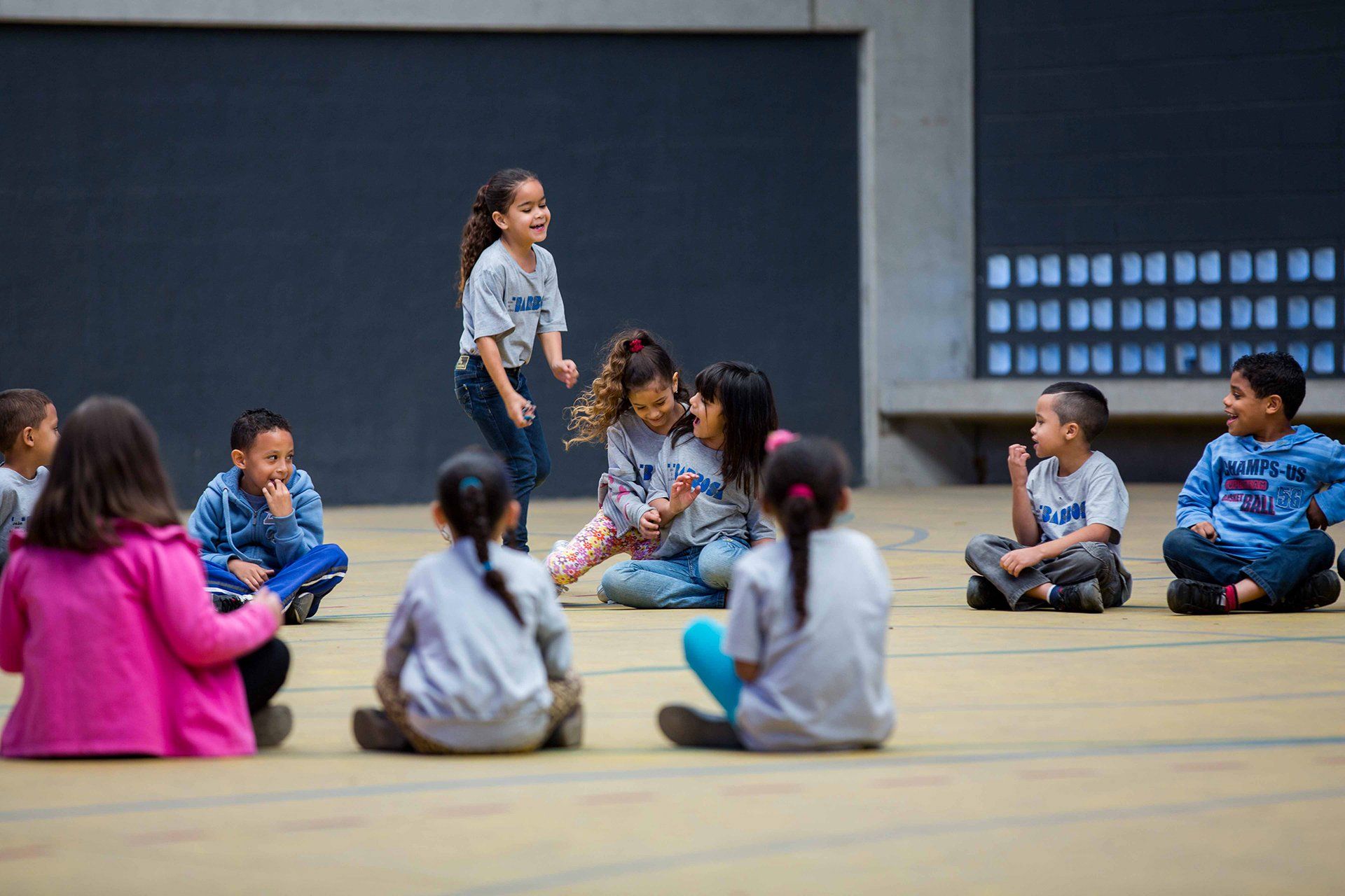 Um grupo de crianças está sentado no chão em círculo.