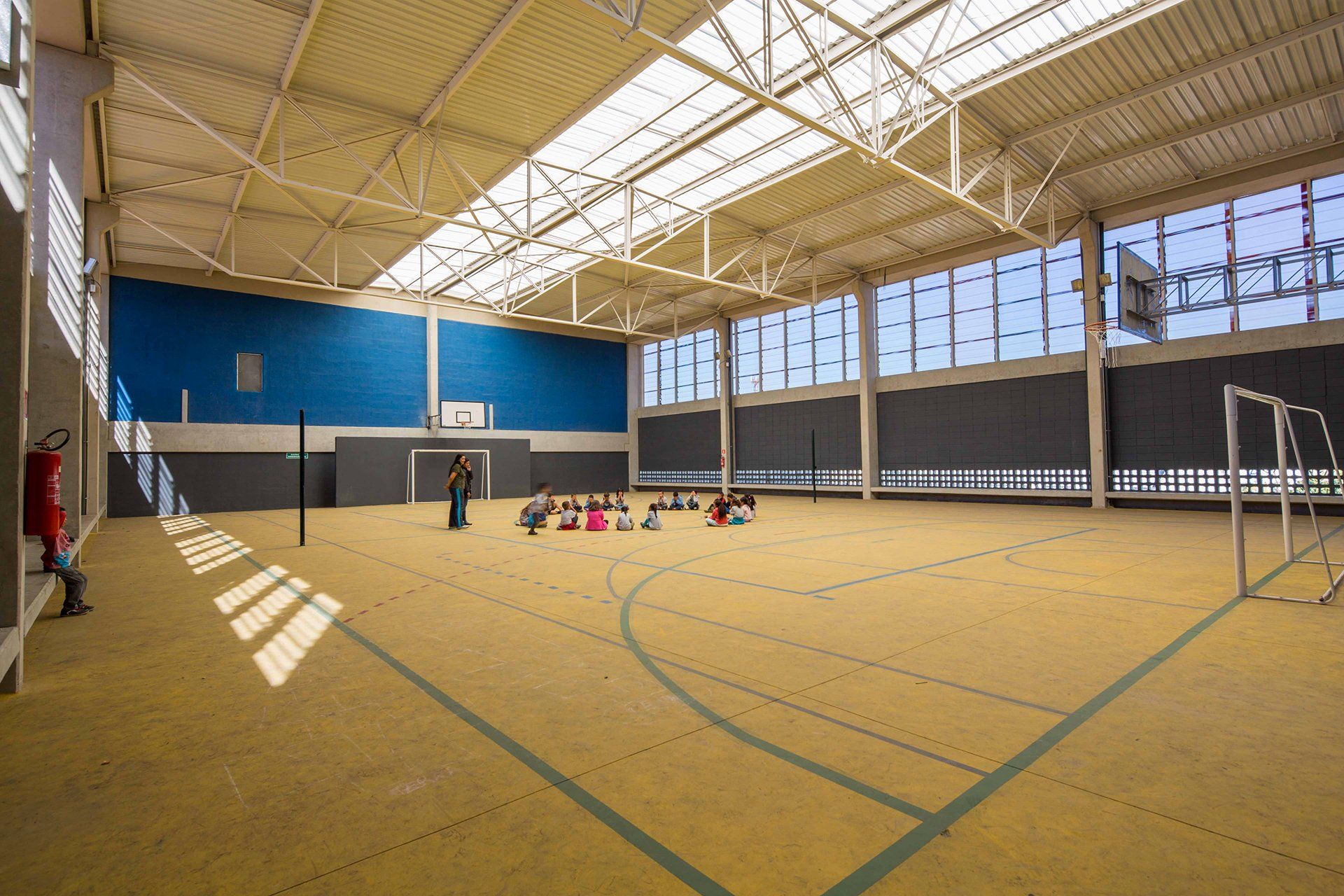 Uma grande academia coberta com quadra de basquete e rede de vôlei.