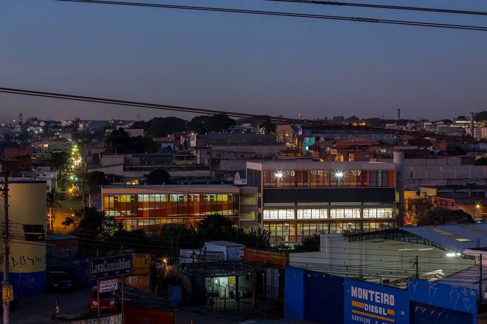 Uma vista aérea de uma cidade à noite com um prédio azul em primeiro plano.