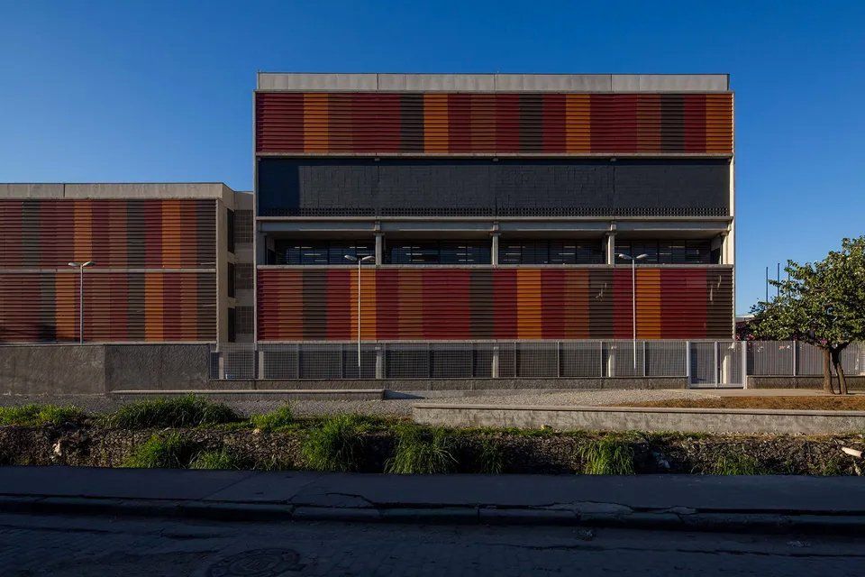 Um grande edifício com uma cerca ao redor e um céu azul ao fundo.