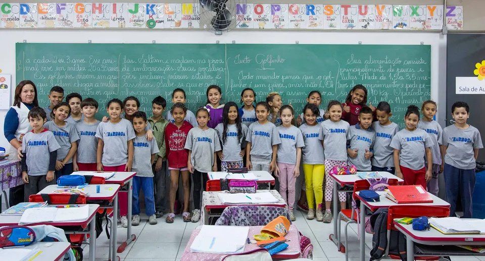 Um grupo de crianças posa para uma foto em uma sala de aula.