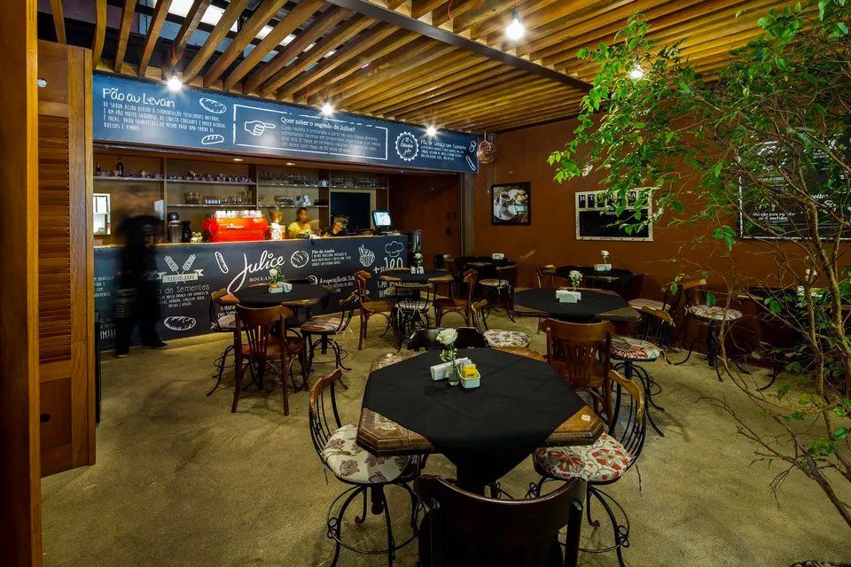 Um restaurante com mesas e cadeiras e um quadro negro na parede