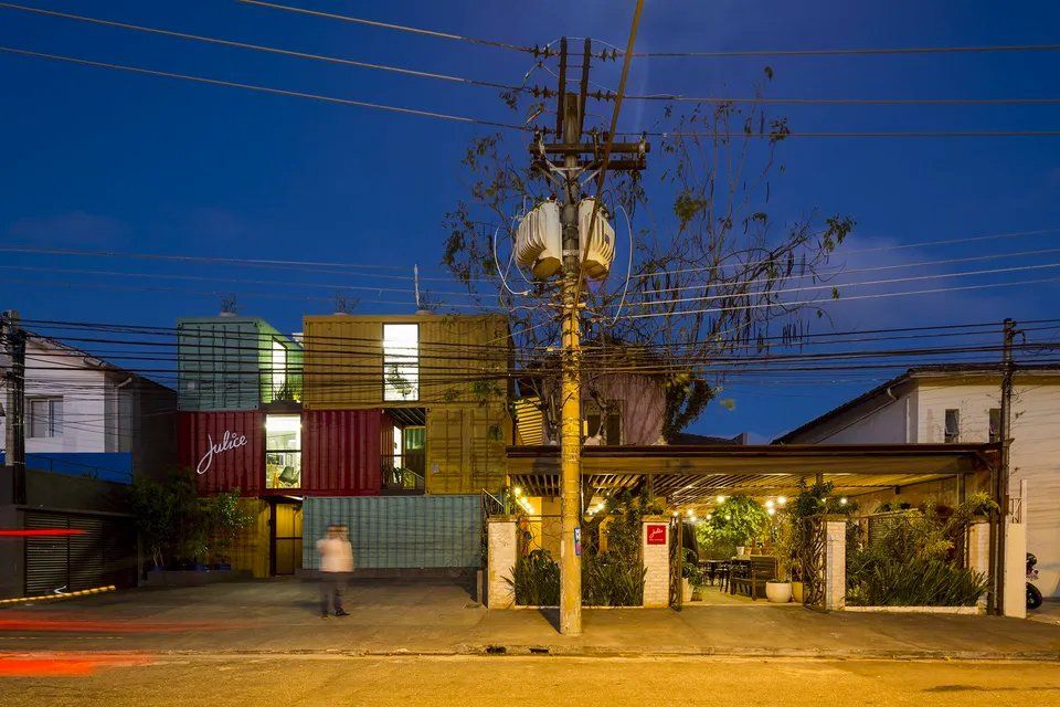 Um prédio feito de contêineres fica iluminado à noite.