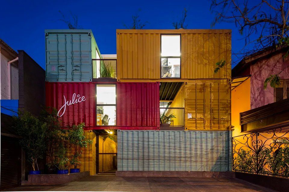Um prédio feito de contêineres fica iluminado à noite.