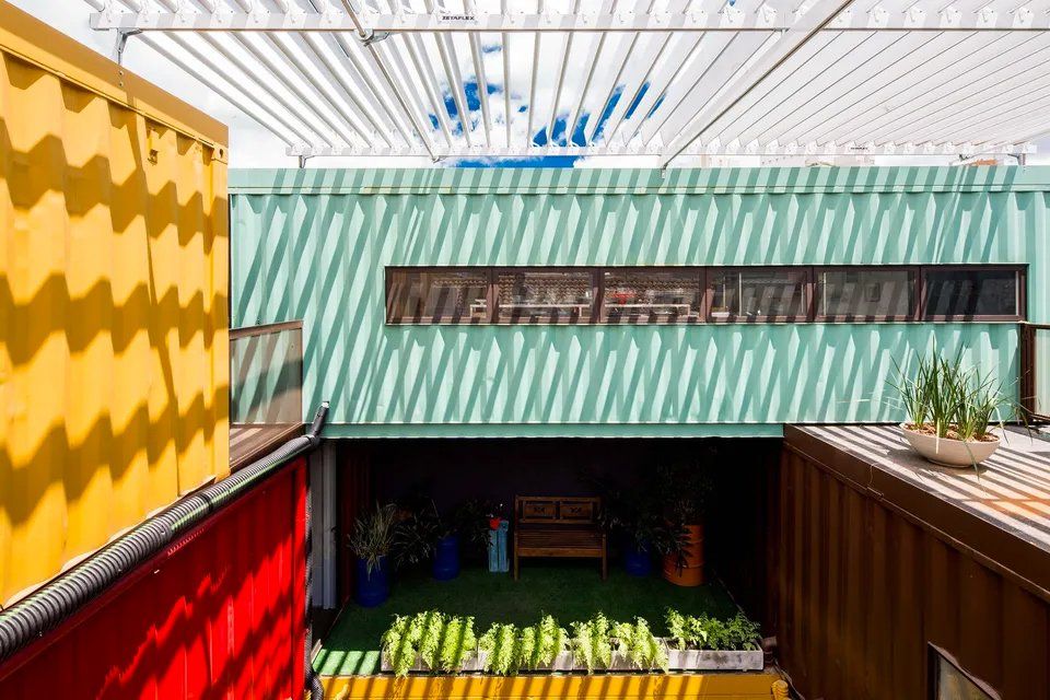 Um prédio feito de contêineres com um pátio no meio.