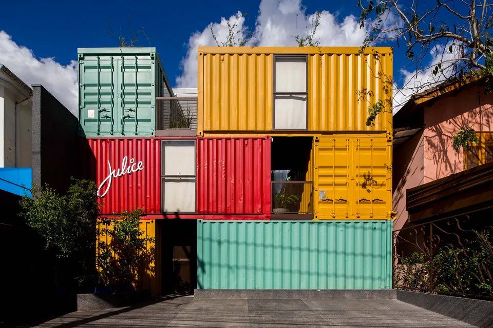Um edifício feito de contêineres é cercado por outros edifícios.