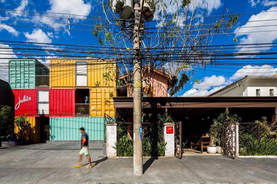 Um homem caminha em frente a um prédio feito de contêineres.