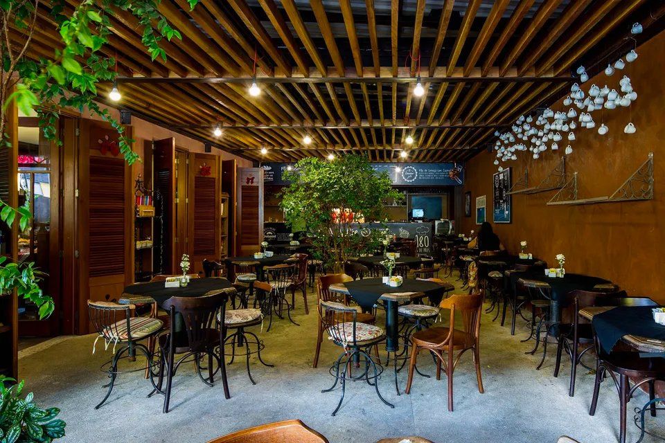 Um restaurante com mesas e cadeiras e uma árvore no meio da sala.