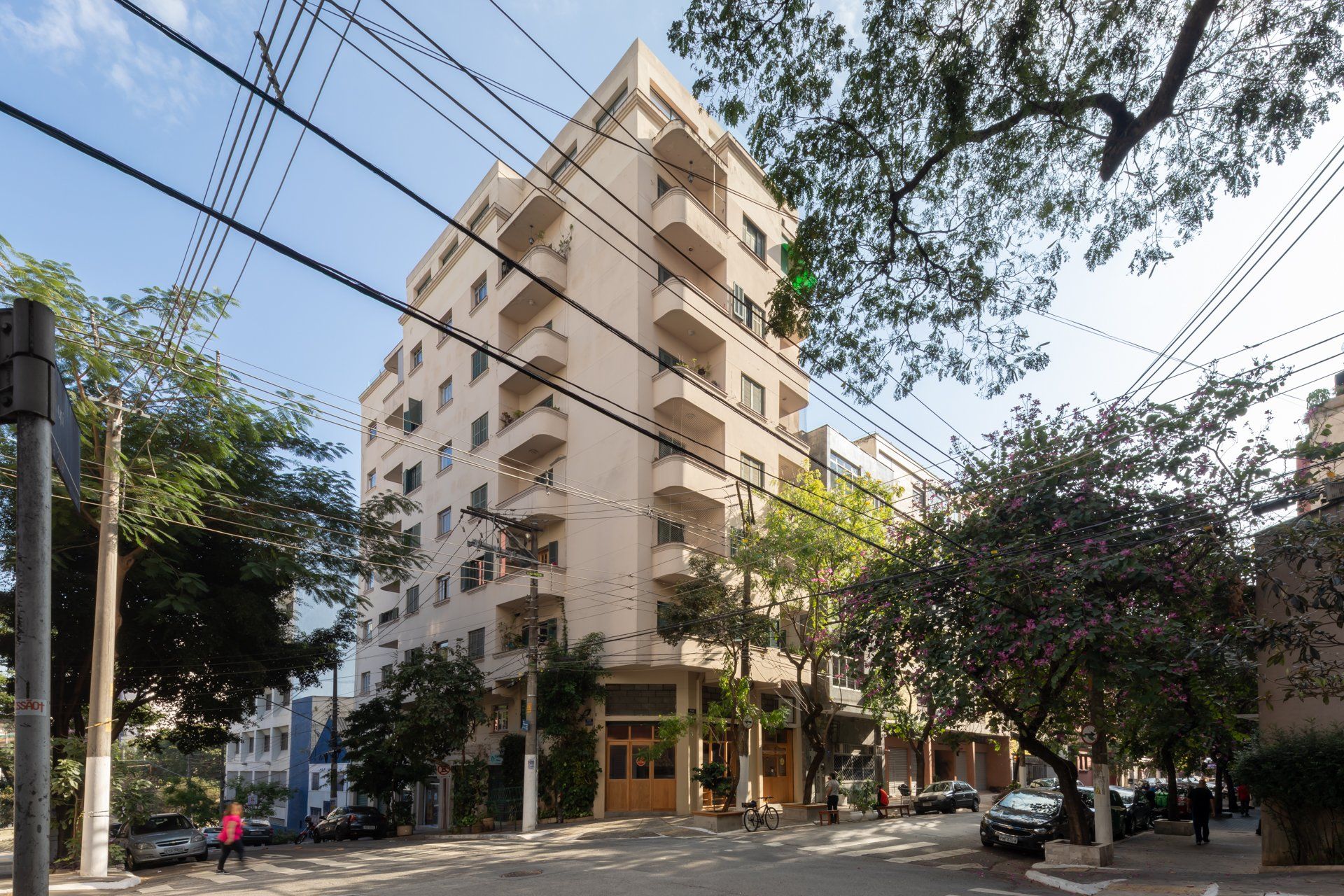 Um prédio com muitas varandas está cercado por árvores e fios