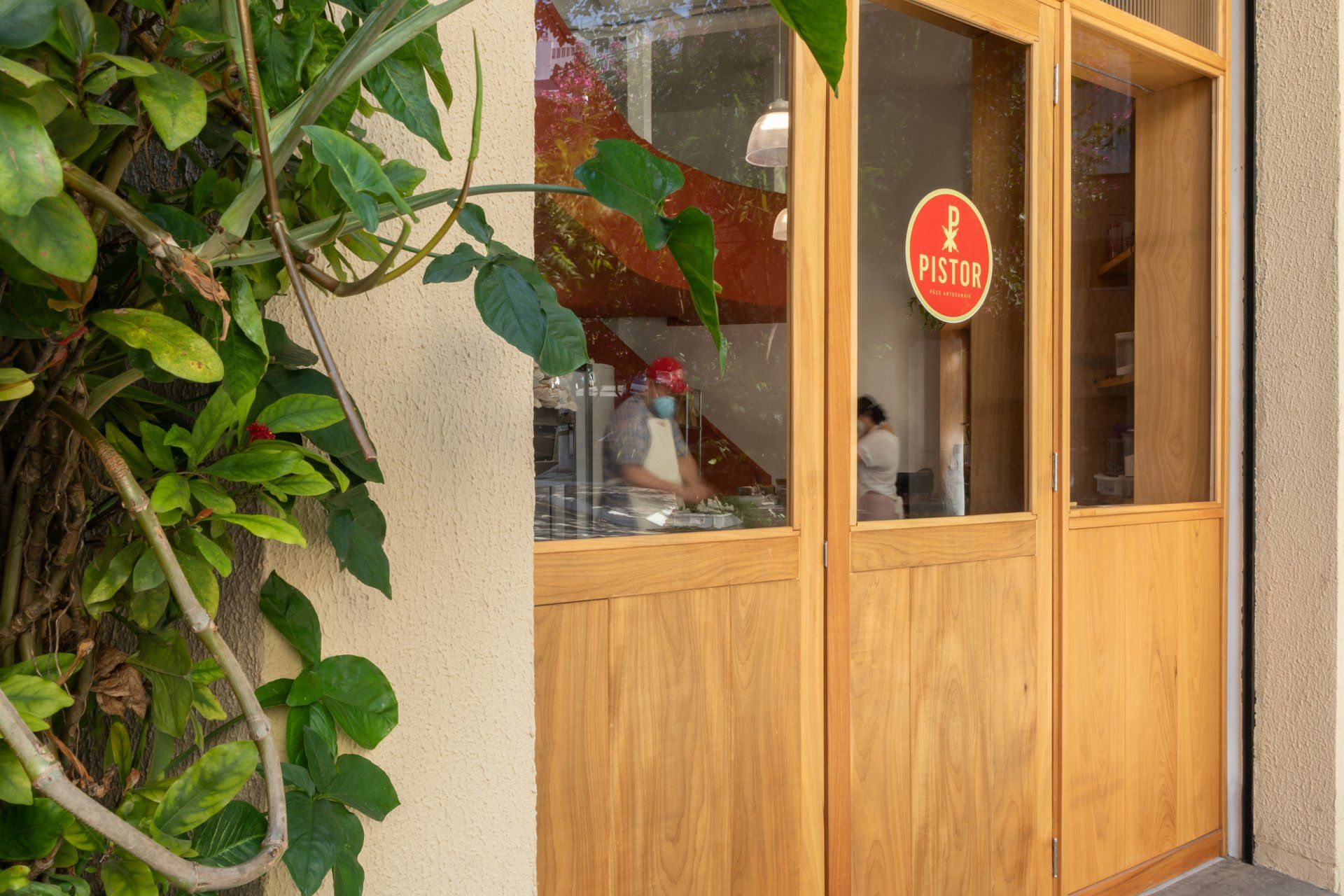Uma porta de madeira com uma placa vermelha está aberta para um restaurante.