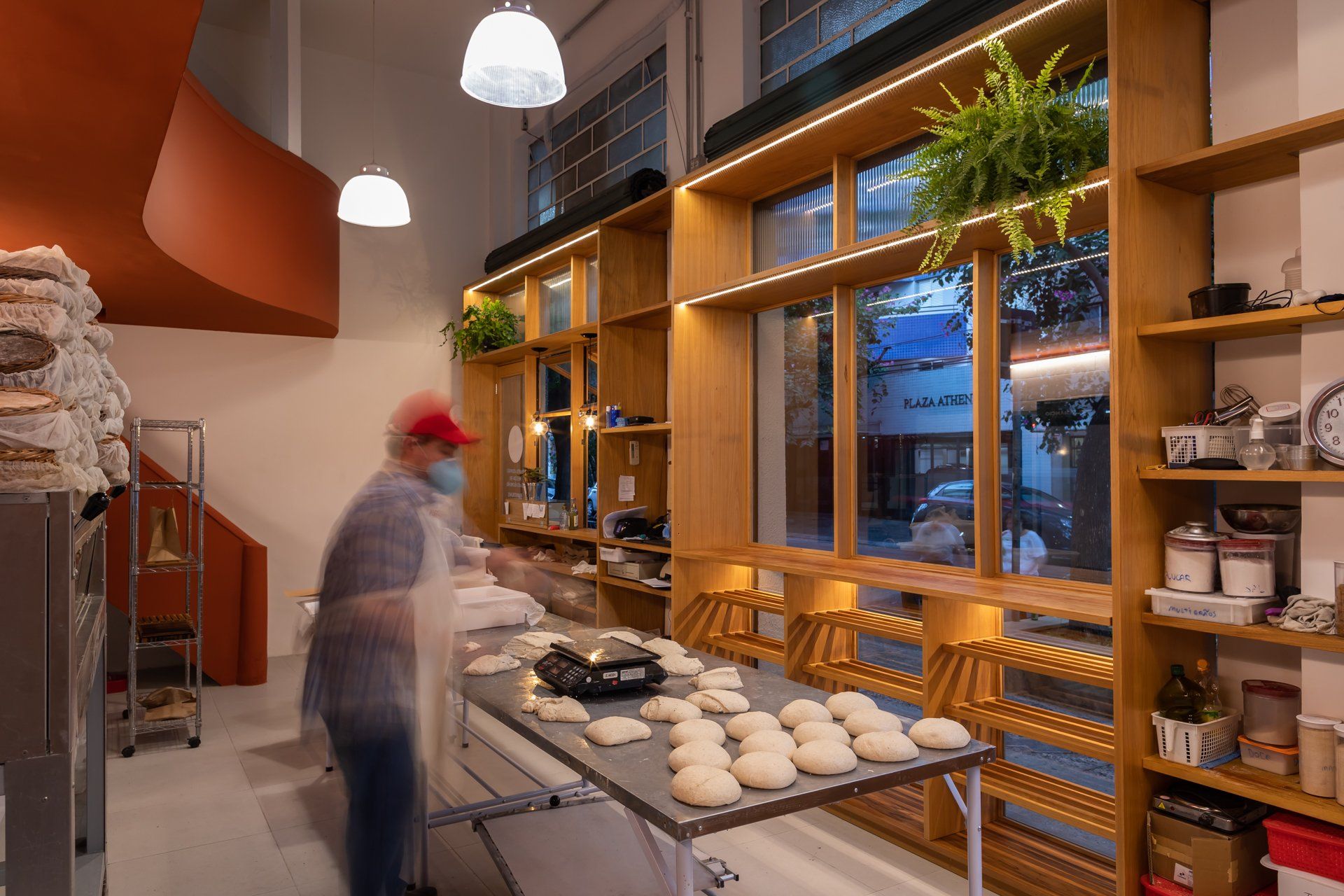 Um homem está em uma padaria preparando massa sobre uma mesa.
