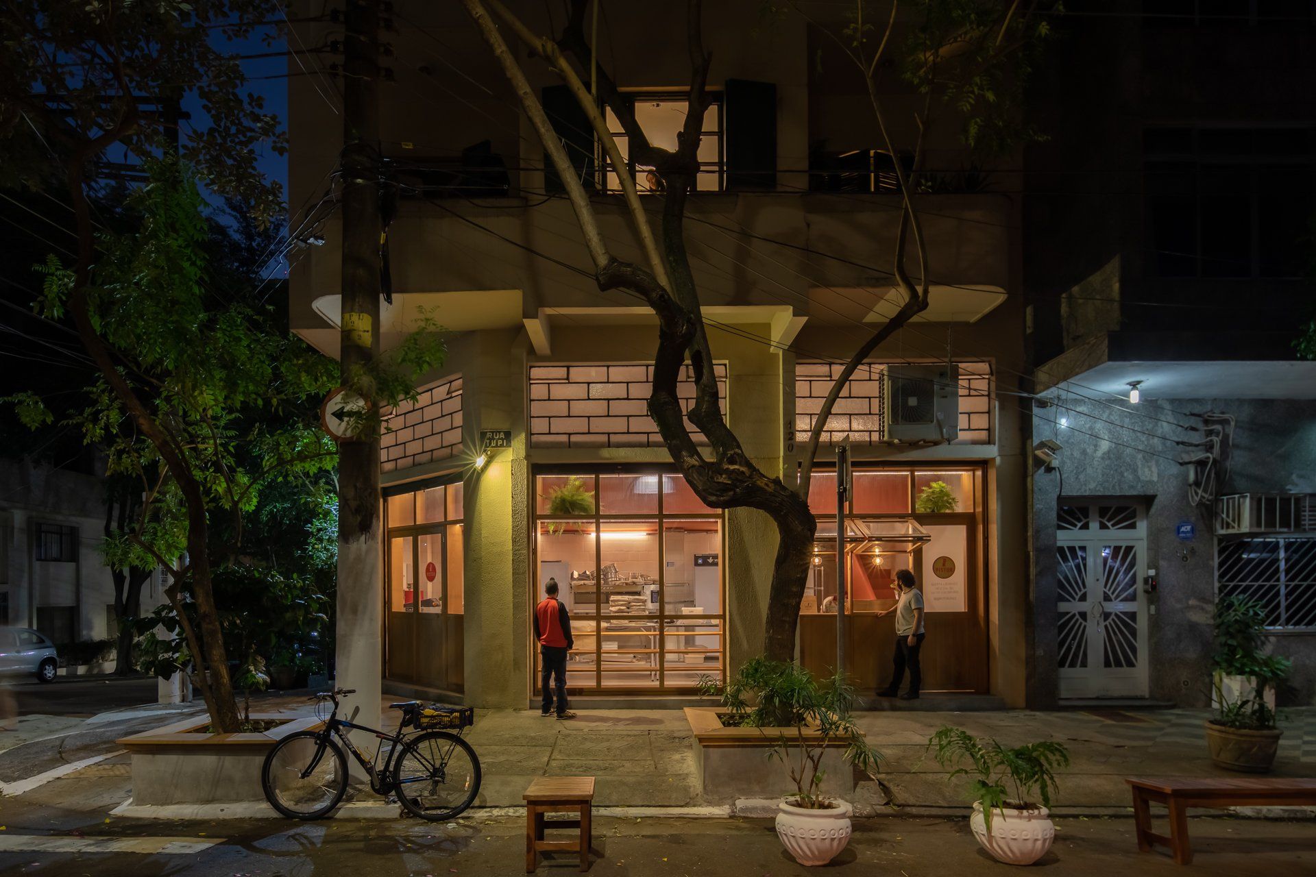 Uma bicicleta está estacionada em frente a um prédio à noite.