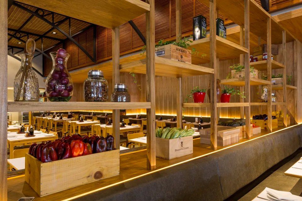 Um restaurante com prateleiras de madeira cheias de comida e legumes.