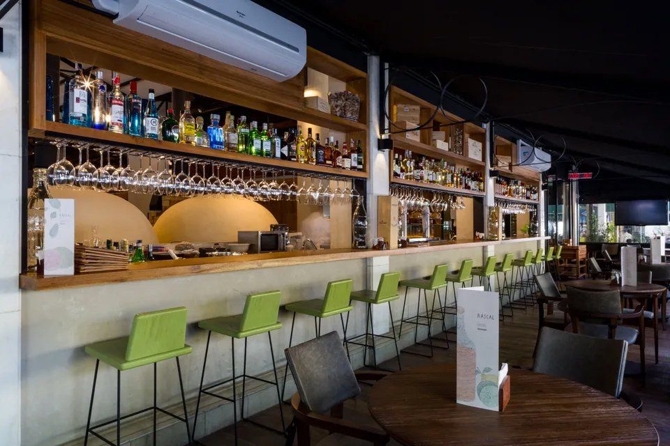 Um restaurante com um longo bar e mesas e cadeiras.