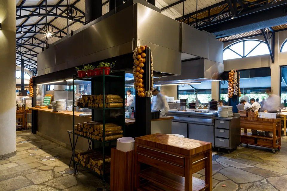 Um restaurante com muitas mesas e cadeiras e uma grande cozinha.