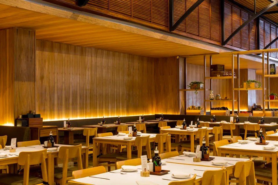 Um restaurante com mesas e cadeiras e teto de madeira.