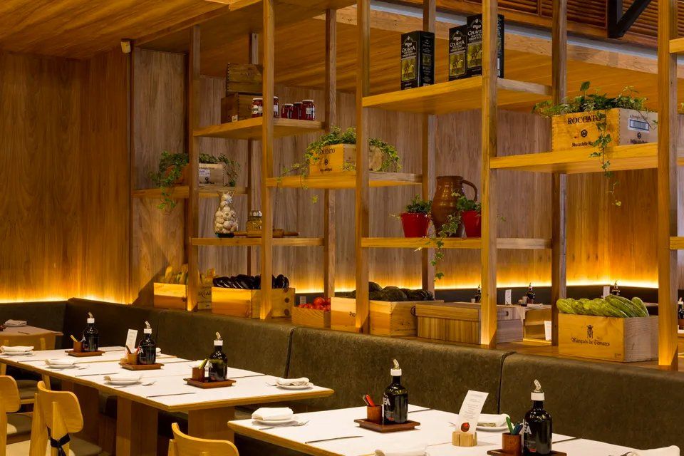 Um restaurante com mesas e cadeiras e prateleiras com plantas.