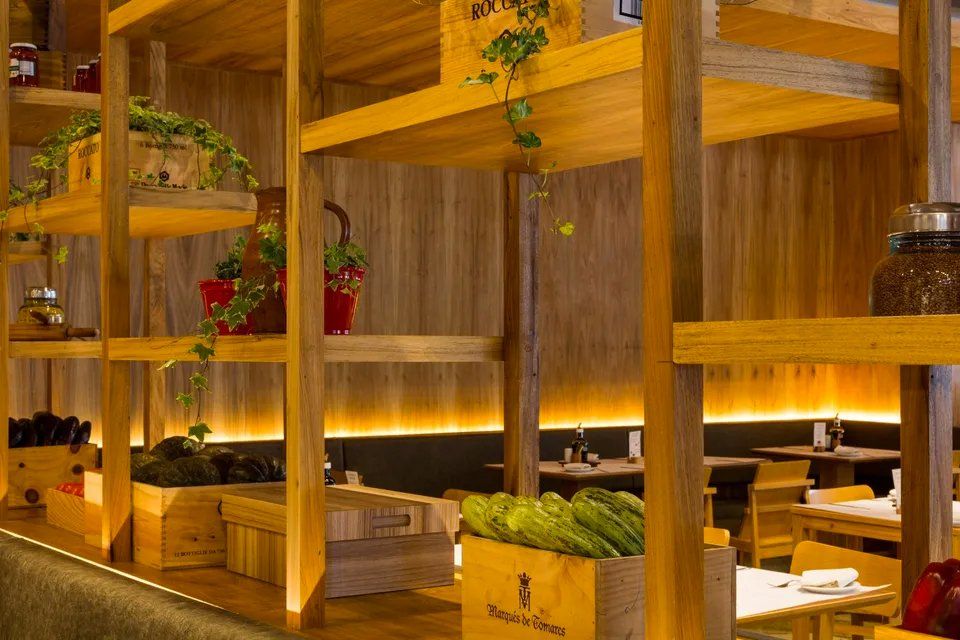 Um restaurante com prateleiras de madeira e mesas e cadeiras.
