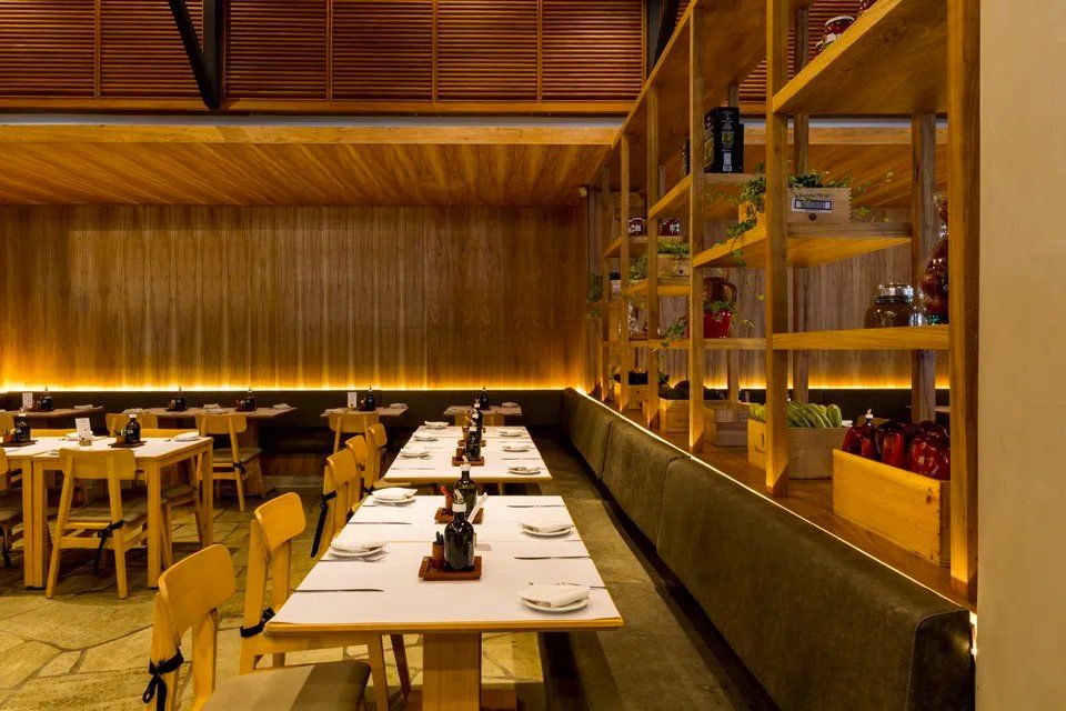 Um restaurante com mesas e cadeiras e prateleiras de madeira.