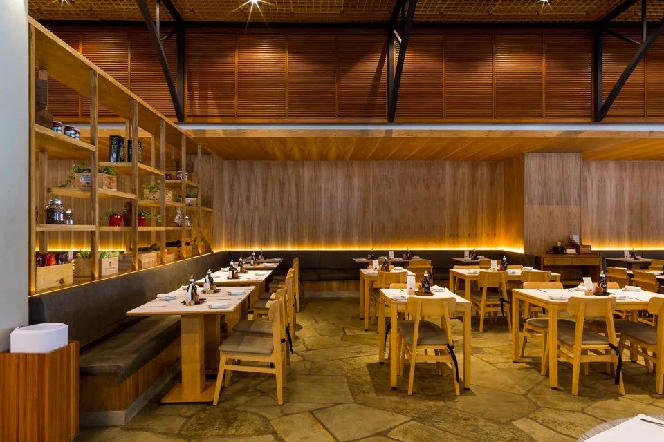 Um restaurante com mesas e cadeiras de madeira e piso de pedra.