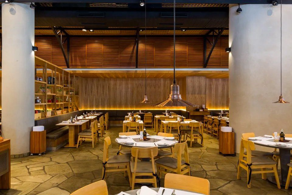 Uma grande sala de jantar com mesas e cadeiras em um restaurante.