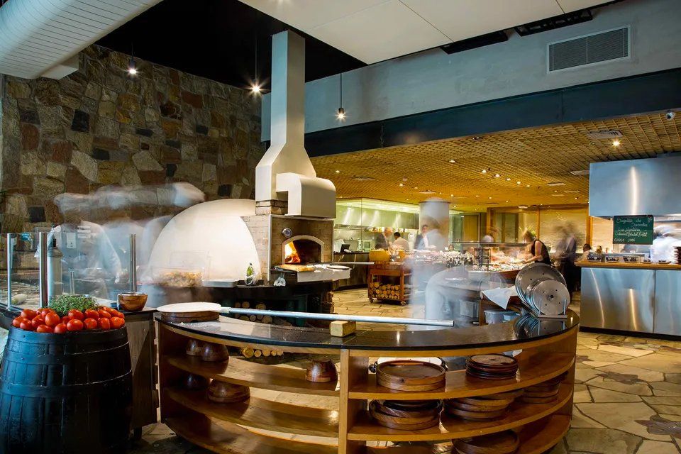 Um restaurante com forno de pizza no meio da sala.